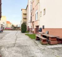 2i byt 43m2 + parkovacie miesto, Hodžova ul., Trenčín - Parkovanie a lavička pred budovou na Hodžovej ulici v Trenčíne, blízko 2-izbového bytu.