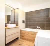 2i byt 43m2 + parkovacie miesto, Hodžova ul., Trenčín - Kúpeľňa so svetlými obkladmi, práčkou a podlahou s dreveným dekorom v 2-izbovom byte.