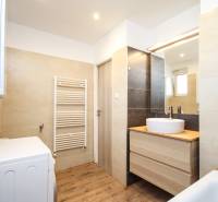 2i byt 43m2 + parkovacie miesto, Hodžova ul., Trenčín - Kúpeľňa v 2-izbovom byte s umývadlom, zrkadlom, práčkou a podlahou s dreveným dekorom.