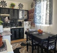 EXKLUZÍVNY PREDAJ - 1 izbový byt, Vodárenská ulica Galanta - Kuchyňa so stôlmi, čiernymi skrinkami a vzorovanými záclonami v 1-izbovom byte.