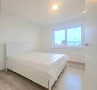 | 4 izbový rodinný dom s krbom a terasov | Slnečná | Ružindol - Spálňa v rodinnom dome s bielou posteľou a podlahou s dreveným dekorom.