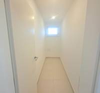 | 4 izbový rodinný dom s krbom a terasov | Slnečná | Ružindol - Úzka biela chodba v rodinnom dome s malým oknom a dlažbou.