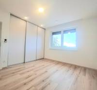 | 4 izbový rodinný dom s krbom a terasov | Slnečná | Ružindol - Izba s podlahou s dreveným dekorom, vstavanou skriňou a oknom v rodinnom dome.