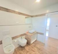 | 4 izbový rodinný dom s krbom a terasov | Slnečná | Ružindol - Kúpeľňa v rodinnom dome s toaletou a bidetom, obklopuje ju podlaha s dreveným dekorom.
