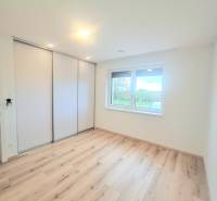 | 4 izbový rodinný dom s krbom a terasov | Slnečná | Ružindol - Izba s podlahou s dreveným dekorom a vstavanou skriňou v rodinnom dome.