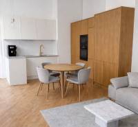 NA PRENÁJOM,Nadštandardný 3-izbový tehlový byt s parkingom,Mlynská ul. - Kuchyňa v 3-izbovom byte s podlahou s dreveným dekorom, sivým kobercom a jedálenským stolom.