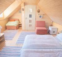 Predaj ,drevená chatka v obci Kráľovce Krnišov - Drevený interiér Chaty s podlahou s dreveným dekorom, posteľou a kreslom.