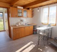 Predaj ,drevená chatka v obci Kráľovce Krnišov - Kuchyňa v Chate s dreveným dekorom a nábytkom, slnečné prostredie.