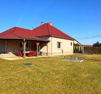 ZĽAVA!! NA PREDAJ RODINNÝ DOM V ZEMIANSKEJ OLČI – PO REKONŠTRUKCII - Rodinný dom v Zemianskej Olči s červenou strechou a dreveným prístreškom, trávnatá záhrada.