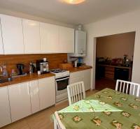 ZĽAVA!! NA PREDAJ RODINNÝ DOM V ZEMIANSKEJ OLČI – PO REKONŠTRUKCII - Kuchyňa v rodinnom dome s bielymi skrinkami, dreveným dekorom a jedálenským stolom.