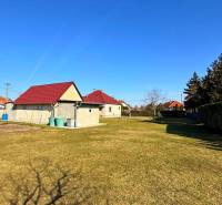 ZĽAVA!! NA PREDAJ RODINNÝ DOM V ZEMIANSKEJ OLČI – PO REKONŠTRUKCII - Trávnatý pozemok pri rodinnom dome v Zemianskej Olči s niekoľkými domami a kríkmi.