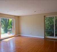 Rodinný dom s veľkou záhradou - Ružinov  - Obývačka s veľkými oknami a podlahou s dreveným dekorom v rodinnom dome.