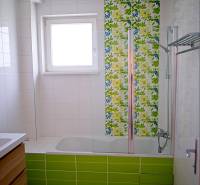 Rodinný dom s veľkou záhradou - Ružinov  - Kúpeľňa v rodinnom dome s vaňou, farebnými obkladmi a oknom pre prirodzené svetlo.