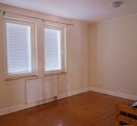 Rodinný dom s veľkou záhradou - Ružinov  - Izba v rodinnom dome, béžové steny, podlaha s dreveným dekorom, dve okná s roletami.