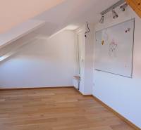 Rodinný dom s veľkou záhradou - Ružinov  - Podkrovná miestnosť s bielou tabuľou a podlahou s dreveným dekorom v rodinnom dome.