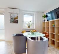 DOBROHOŠŤ- Prenájom  3i zariadeného bytu s predzáhradkou a parkingom - Jedálenský kút v 3-izbovom byte s preskleným stolom, sivými kreslami a dreveným dekorom podlahy.