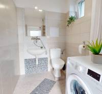 DOBROHOŠŤ- Prenájom  3i zariadeného bytu s predzáhradkou a parkingom - Kúpeľňa v 3-izbovom byte s práčkou, toaletou, umývadlom a rastlinou. Biele obklady.