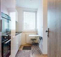 2 byty v 1 už s nájomníkmi | okamžitý príjem 1600 €/mes | 4.87% - Kuchyňa v 3-izbovom byte s lesklou skriňou, skladacími stoličkami a výhľadom.