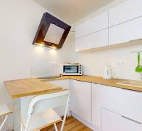 2 byty v 1 už s nájomníkmi | okamžitý príjem 1600 €/mes | 4.87% - Kuchyňa v 3-izbovom byte s barovým pultom a bielymi skrinkami, podlaha s dreveným dekorom.