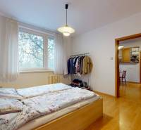 Veľkometrážny 3i byt s výťahom a pivnicou | Ružinov | 82m2 - Spálňa v 3-izbovom byte s posteľou, šatníkom a podlahou s dreveným dekorom.
