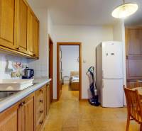 Veľkometrážny 3i byt s výťahom a pivnicou | Ružinov | 82m2 - Kuchyňa v 3-izbovom byte s bielymi spotrebičmi, drevenými skrinkami a oknom.