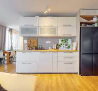 2 byty v 1 už s nájomníkmi | okamžitý príjem 1770€/mes | 4.08% - Kuchyňa s bielymi skrinkami, čiernou chladničkou a podlahou s dreveným dekorom v 5 a viac izbovom byte.