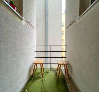 5iz byt s vysokými stropmi a výťahom pri EUROVEA | 136 m² - Balkón v 5 a viac izbovom byte s umelým trávnikom a dvoma drevenými stoličkami.