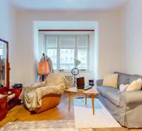 5iz byt s vysokými stropmi a výťahom pri EUROVEA | 136 m² - Obývacia izba s pohovkou, kreslom, stolom, podlahou s dreveným dekorom a veľkým oknom.