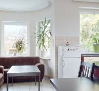 4-izbový samostatne stojaci dom s garážou | Podunajské Biskupice - Kuchyňa rodinného domu s koženým gaučom, stolom, rastlinami, chladničkou a oknami.