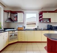 4-izbový samostatne stojaci dom s garážou | Podunajské Biskupice - Kuchyňa v rodinnom dome s krémovými skriňami, digestorom a výhľadom do záhrady.