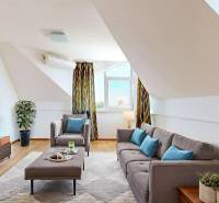 2iz byt v novostavbe s parkovaním | Podunajské Biskupice | 57m2 - Podkrovný obývací priestor s pohodlnou sedačkou, televízorom a podlahou s dreveným dekorom.