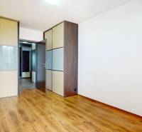 2iz byt v novostavbe s parkovaním | Podunajské Biskupice | 57m2 - Izba s bielymi stenami, vstavanou skriňou a podlahou s dreveným dekorom v 2-izbovom byte.