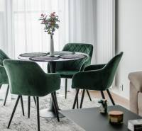 | E2Tower | 20.poschodie | 2i byt | panoramatický výhľad |  - Zelené kreslá a stôl s kvetom v 2-izbovom byte na podlahe s dreveným dekorom.