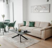 | E2Tower | 20.poschodie | 2i byt | panoramatický výhľad |  - Obývacia izba v 2-izbovom byte so svetlým gaučom a zelenými kreslami.