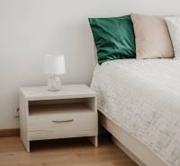 | E2Tower | 20.poschodie | 2i byt | panoramatický výhľad |  - Nočný stolík s lampou pri posteli, 2-izbový byt, podlaha s dreveným dekorom.