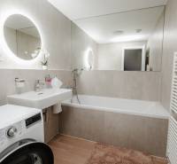 | E2Tower | 20.poschodie | 2i byt | panoramatický výhľad |  - Kúpeľňa v 2-izbovom byte s umývadlom, vaňou a práčkou, dlažba s dreveným dekorom.