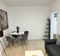 NA PREDAJ ŠTÝLOVÝ 2- IZBOVÝ BYT, 50m2, SÍDLISKO 2, PREŠOV - Obývačka v 2-izbovom byte s podlahou s dreveným dekorom, sivou sedačkou a jedálenským stolom.