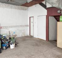 4-izbový podkrovný byt s nebytovým priestorom v obci Pavlice - Garáž v rodinnom dome, odložené náradie, betónová podlaha, schody a biely nábytok.