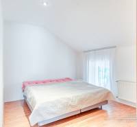 4-izbový podkrovný byt s nebytovým priestorom v obci Pavlice - Spálňa v rodinnom dome s veľkou posteľou a podlahou s dreveným dekorom.
