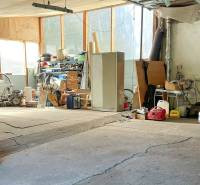 4-izbový podkrovný byt s nebytovým priestorom v obci Pavlice - Garáž v rodinnom dome plná nástrojov a strojov, s rôznym vybavením na policiach.