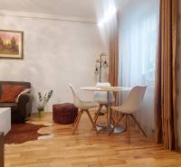 Vkusný, moderný 2 izb, klíma, 870 s ener., Sibírska ul./Nové Mesto - Obývacia izba v 2-izbovom byte s koženou sedačkou a jedálenským stolom, podlaha s dreveným dekorom.