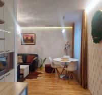 Vkusný, moderný 2 izb, klíma, 870 s ener., Sibírska ul./Nové Mesto - Obývacia izba v 2-izbovom byte s podlahou s dreveným dekorom a jedálenským stolom.