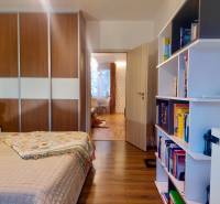 Vkusný, moderný 2 izb, klíma, 870 s ener., Sibírska ul./Nové Mesto - Spálňa v 2-izbovom byte s podlahou s dreveným dekorom, vstavanou skriňou a knižnicou.