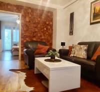 Vkusný, moderný 2 izb, klíma, 870 s ener., Sibírska ul./Nové Mesto - Obývacia izba v 2-izbovom byte s koženou sedačkou, stolíkom a stenou s dreveným dekorom.