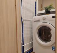 Vkusný, moderný 2 izb, klíma, 870 s ener., Sibírska ul./Nové Mesto - Práčka v kúpeľni 2-izbového bytu, vedľa sušiak a police s dekoráciou.