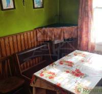 Pôvodná goralská drevenica, Osturňa - Izba v rodinnom dome s dreveným obložením, kvetinovým obrusom a záclonami.