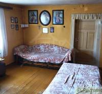 Pôvodná goralská drevenica, Osturňa - Interiér rodinného domu s drevenou podlahou, stoly, stoličky, nástenné dekorácie.