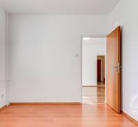 NEZARIADENÝ 2,5-izb.byt, 11m2 LODŽIA, BA IV., Červeňákova - Izba so stenami v bielej farbe, podlahou s dreveným dekorom a oknom so žalúziami.