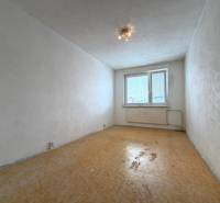 Predaj 2 - izbového bytu v Banskej Štiavnici - Prázdna izba v 2-izbovom byte s bielymi stenami a podlahou s dreveným dekorom.