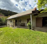 Predaj domu v Janovej Lehote - Rodinný dom v Janovej Lehote so záhradou a lesom v pozadí pod oblačnou oblohou.